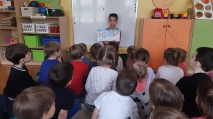 Dzieci słuchają opowiadania czytanego przez absolwenta.