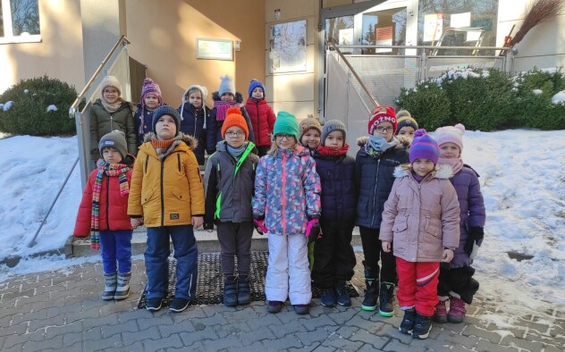 Dzieci stoją przed budynkiem szkoły